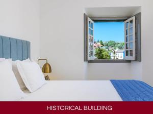 a bedroom with a white bed and a window at Casa Senhoras Rainhas AL - Obidos - by Unlock Hotels in Óbidos