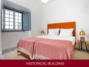 a bedroom with a bed with a red blanket and a window at Casa Senhoras Rainhas AL - Obidos - by Unlock Hotels in Óbidos