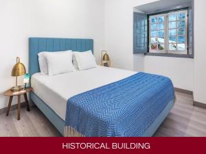 a bedroom with a blue and white bed and a window at Casa Senhoras Rainhas AL - Obidos - by Unlock Hotels in Óbidos
