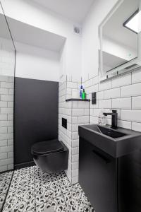 baño con aseo negro y lavamanos en Apartament Alpaka 2, en Lidzbark Warmiński