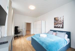 Schlafzimmer mit einem blauen Bett und einem Schreibtisch in der Unterkunft Room&Go: Zentral - Terrasse - Weber Grill in Halle an der Saale