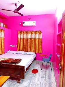 - une chambre rose avec un lit et une chaise dans l'établissement Rabindra Bilas Homestay, à Bolpur
