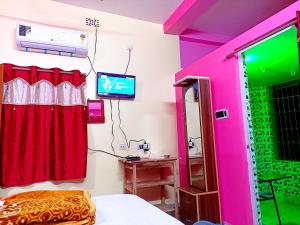 Cette chambre comprend un lit et une télévision murale. dans l'établissement Rabindra Bilas Homestay, à Bolpur