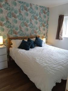 a bedroom with a white bed with blue pillows at The Old Garage in West Itchenor