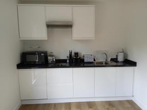 a kitchen with white cabinets and a sink at The Old Garage in West Itchenor