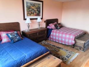 a bedroom with two beds and a table with lamps at Hermosa cabaña en Amealco centro in Amealco