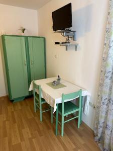 a table with two chairs and a tv on a wall at Longa Rooms in Šibenik