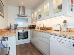 a kitchen with marble counter tops and white cabinets at Lemon Tree in Falmouth