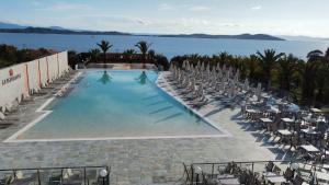 a swimming pool with chairs and the ocean in the background at Aristoteles Holiday Hotel And Spa in Ouranoupoli