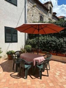 a table and chairs with an umbrella on a patio at Longa Rooms in Šibenik