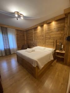 1 dormitorio con 1 cama grande y paredes de madera en Hotel Oasi en San Vito di Cadore