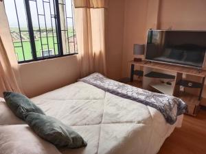 um quarto com uma cama, uma televisão e uma janela em Casa Rural Zaba Lago de Tota em Aquitânia