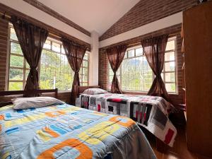 two beds in a room with windows at EL HATO HOME REST in Cachipay