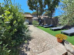 een tuin met een stenen pad en bankjes bij JOLI MAZET ST TROPEZ in Gassin