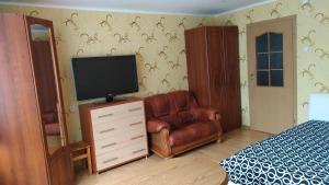 1 dormitorio con TV y silla de cuero en Visaginas Taikos 84, en Visaginas