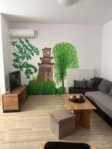 uma sala de estar com um sofá e uma torre de relógio pintada na parede em Bakopoulos Resort Ένα όμορφο και ήσυχο διαμέρισμα στα Τρίκαλα em Trikala