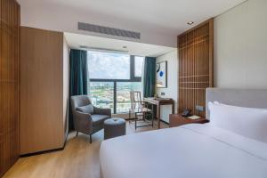 a hotel room with a bed and a chair and a window at Huawen Four Season Hotel in Zhaoqing