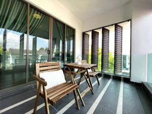 einen Holztisch und Stühle auf einem Balkon mit Fenstern in der Unterkunft Solitude Staycation By HomestayJB in Kangkar Pendas