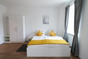 a bedroom with a white bed with yellow sheets and a window at WeinlandMotel in Ebenthal