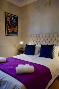 1 dormitorio con 1 cama grande con sábanas moradas y almohadas azules en Spacious 3 Bedroom Home Green Point, en Ciudad del Cabo