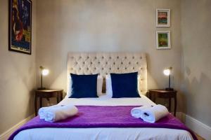 1 dormitorio con 1 cama grande con sábanas moradas y almohadas azules en Spacious 3 Bedroom Home Green Point, en Ciudad del Cabo