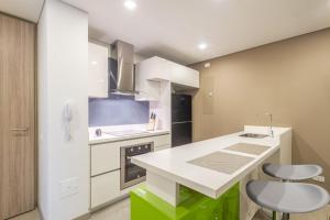a kitchen with a white counter and some chairs at Apartamento moderno in Bogotá