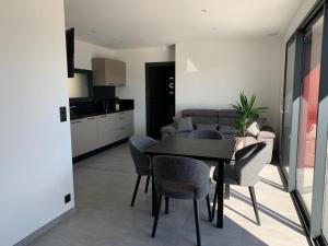 a dining room with a table and chairs and a kitchen at Les Restanques du lac in La Chapelle