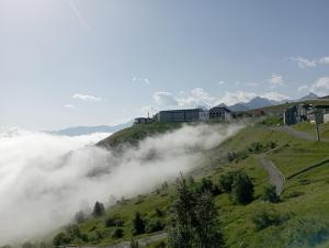 Une colline brumeuse avec des maisons en haut dans l'établissement Appt 4 pers au Pla d' Adet, Résidence le Grand Stemm , station de ski Saint Lary, à Saint-Lary-Soulan
