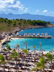 una playa con sillas y sombrillas y el océano en Mucobega Hotel, en Sarandë