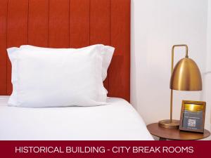 a bed with a white pillow and a lamp on a table at Casa Senhoras Rainhas AL - Obidos - by Unlock Hotels in Óbidos