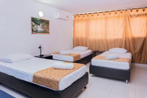 a bedroom with three beds and a window at Hotel Sol Inn Santa Marta in Santa Marta