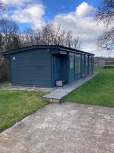 un gran edificio azul con un porche en un patio en Littlewood Cabin, en Hatherleigh
