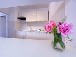 a vase with pink flowers sitting on a counter in a kitchen at Apartments Villa Marijeta with Free Parking in Zaton