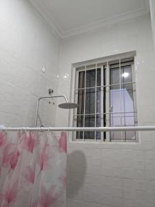 a bathroom with a shower curtain and a window at Mninga Classic Lodge, Ilazo in Dodoma