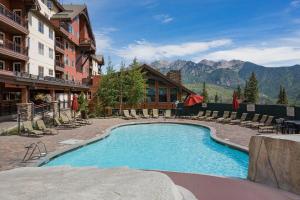 a swimming pool in a resort with chairs and mountains at Village Center 611 in Durango Mountain Resort