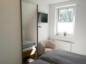 a mirror in a bedroom with a bed and a chair at Seehaus Luddenhof 1 - a90196 in Walchum