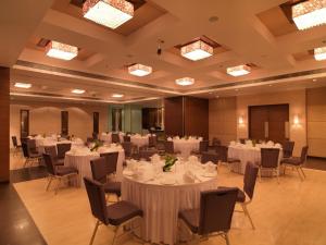 un salón de banquetes con mesas y sillas blancas en Spree Shivai Hotel Pune, en Pune