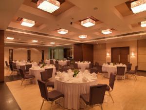 浦那Spree Shivai Hotel Pune的摆放着白色桌椅的宴会厅