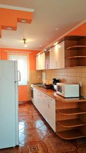 cocina con paredes de color naranja y nevera blanca en Casa Flamingo, en Sovata