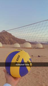 una persona che tiene una palla da pallavolo davanti a un pallone da calcio di Aljawhara camp and activities a Wadi Rum