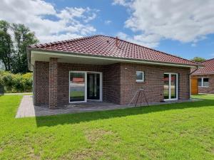 a small brick house with a lawn in front of it at Ferienhaus Seebrise - a90185 in Walchum