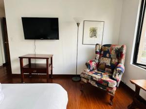 um quarto com uma cama, uma cadeira e uma televisão em Spacious Apartment in Bellavista - Beautiful City Views em Quito
