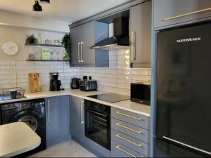 cocina con armarios azules y lavavajillas en Sea Renity Apartment, en Newcastle