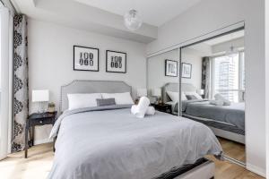 a bedroom with a large bed and a mirror at Cozy Downtown 2BR Suite near CN Tower with Balcony in Toronto