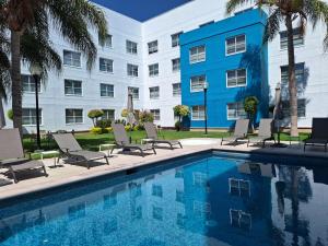 einem Pool vor einem Hotel mit Stühlen und einem Gebäude in der Unterkunft Sierra Suites By HP Hotels in San Luis Potosí