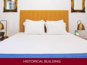 a bedroom with a bed with white sheets and pillows at Casa Senhoras Rainhas AL - Obidos - by Unlock Hotels in Óbidos +9 photos