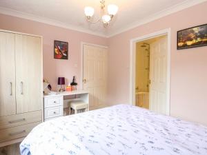 a bedroom with a white bed and a desk at Deer Cottage in Thompson