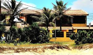 Pousada na Praia Maricá في ماريكا: منزل اصفر امامه اشجار النخيل