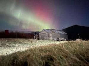 a tripod in front of a barn with a rainbow in the sky at Croisgeir Self Catering Pod in Daliburgh