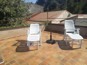 3 weiße Stühle auf einer Terrasse in der Unterkunft La Dimora di Anna in Praia a Mare